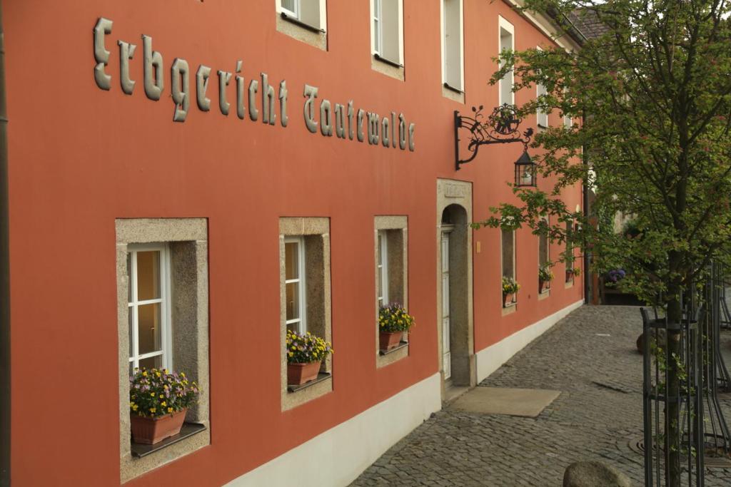 an orange building with potted plants on a street at Landidyll Hotel Erbgericht Tautewalde in Wilthen