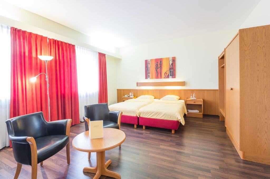 Una habitación de hotel con una cama, una mesa y sillas. en Logis Hôtel Acacia, en Esch-sur-Alzette