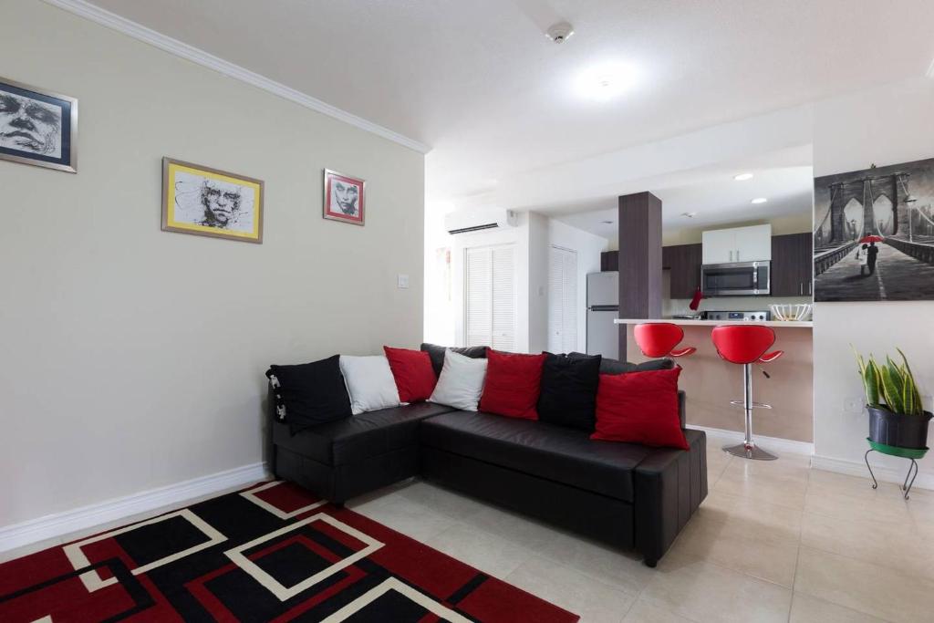 a living room with a black couch and red pillows at The Brompton's Luxury Apartment in Kingston