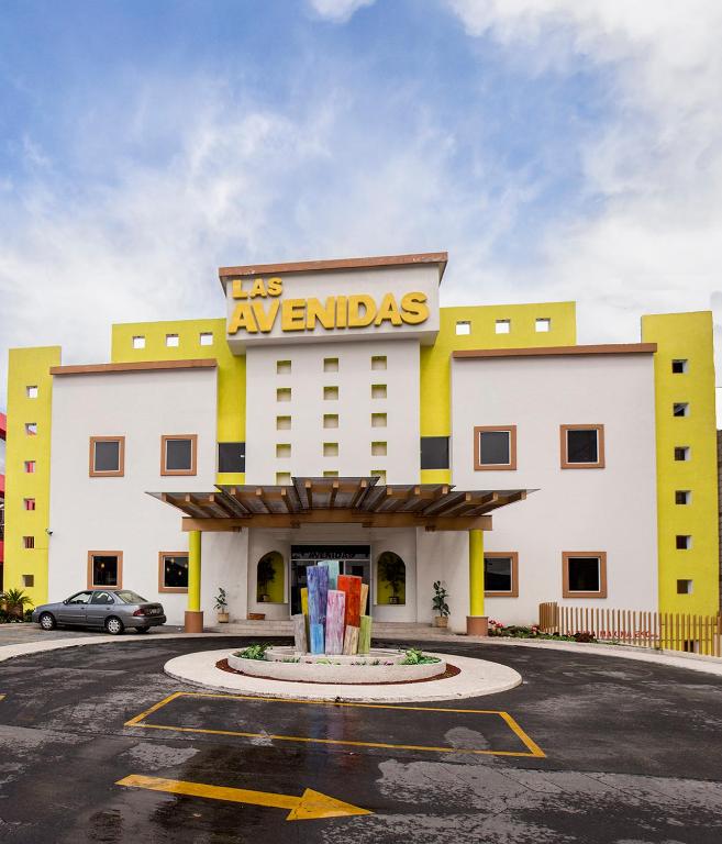un edificio blanco y amarillo con un letrero. en Las Avenidas, en Pachuca de Soto