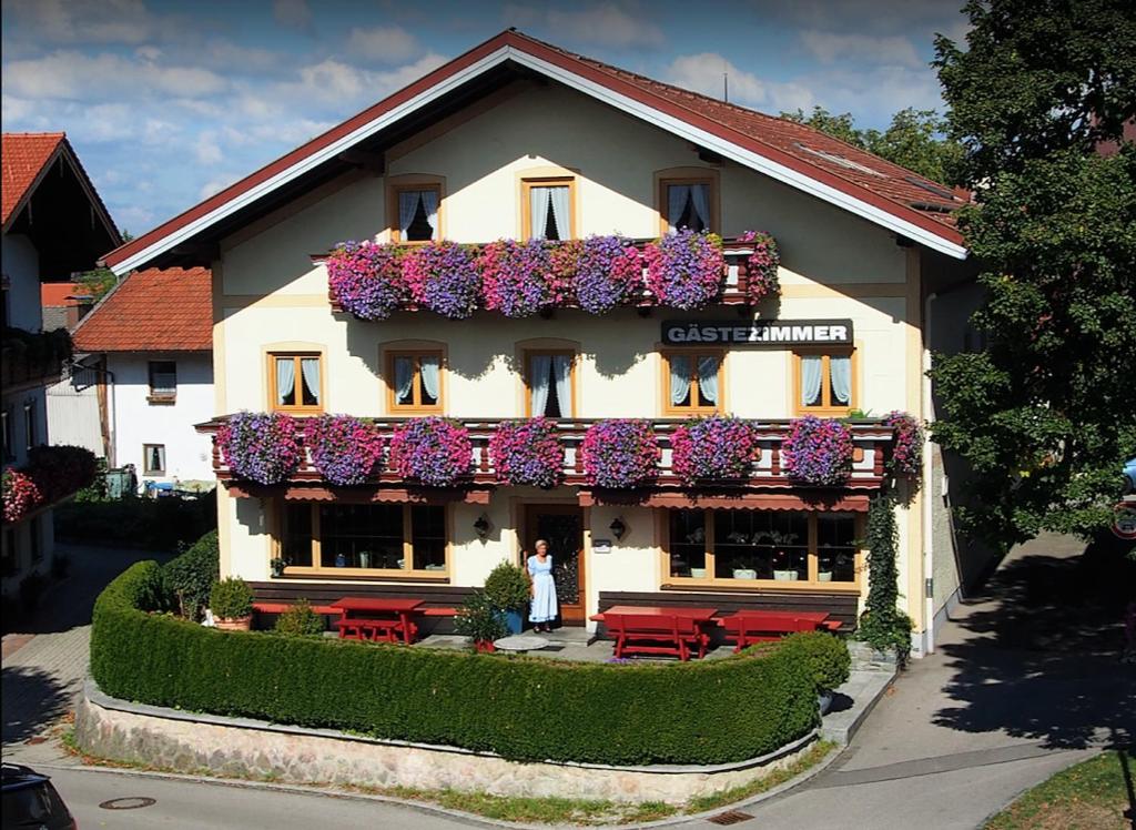 a woman standing in front of a building with flowers at Pension Langerspacher in Grabenstätt