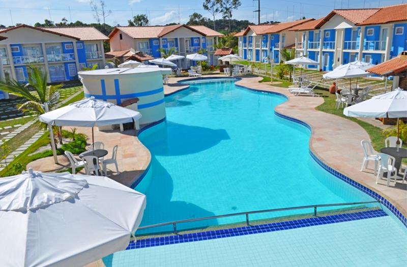 una piscina en un complejo con sombrillas en Ap (Flat) Taperapuã Porto Seguro en Porto Seguro