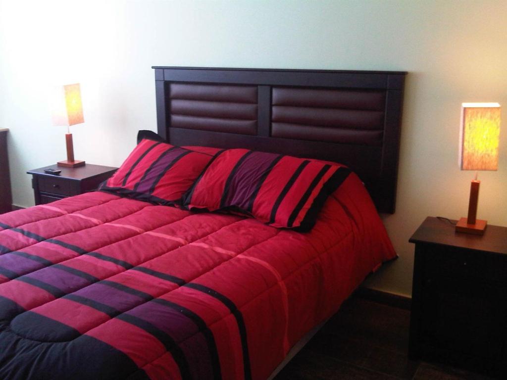 a bedroom with a large red bed with two lamps at Apart Magallanes in Santiago