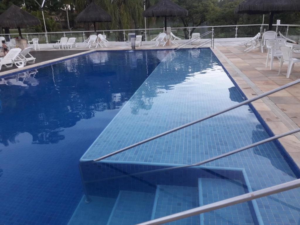 a large swimming pool with white chairs and umbrellas at Boituva Rancho dos Arcos in Boituva