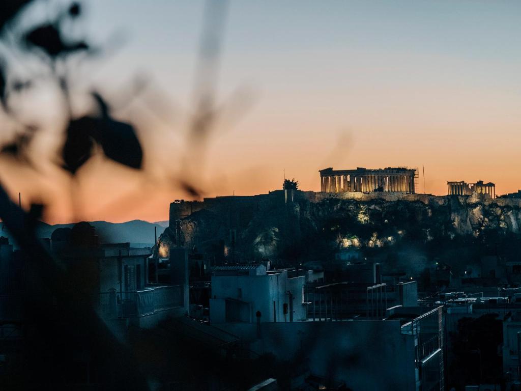 a view of the acropolis from a city at sunset at Penthouse in Kolonaki in Athens