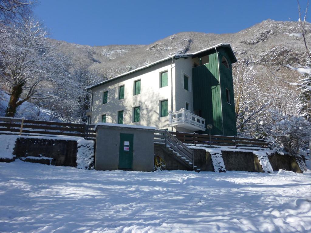 a building with a green door in the snow at Appartements Les Pins in Cierp