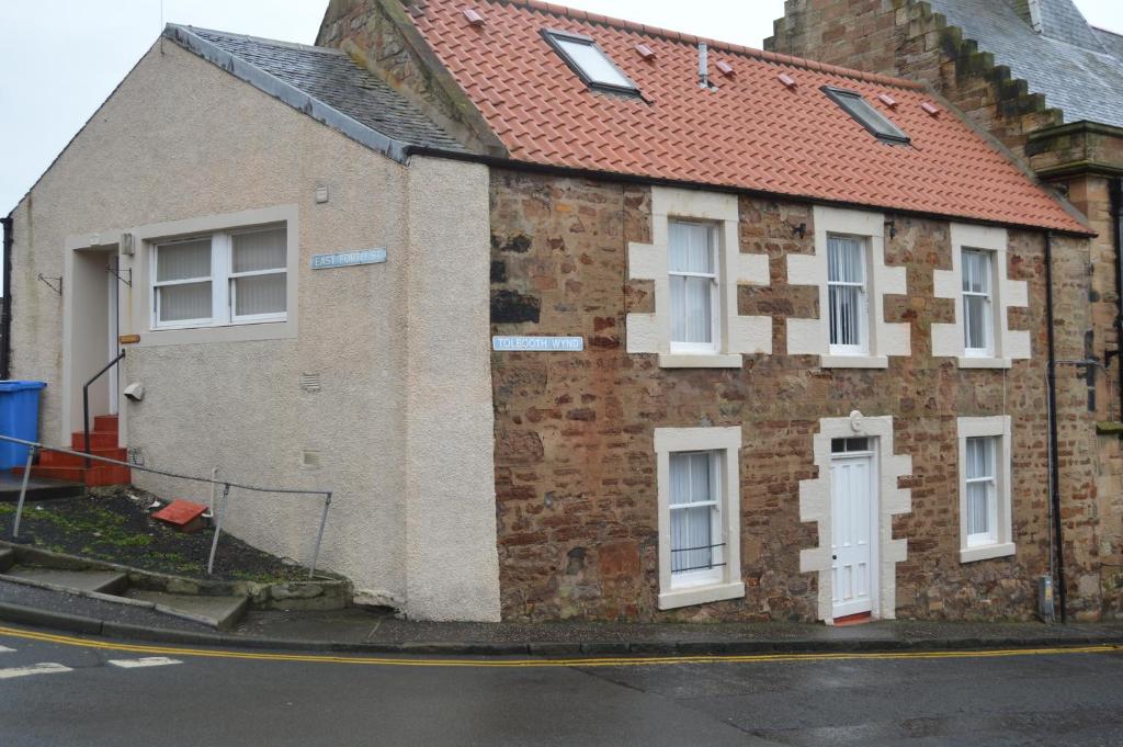 a brick house with white windows and a red roof at Cruachan in Cellardyke