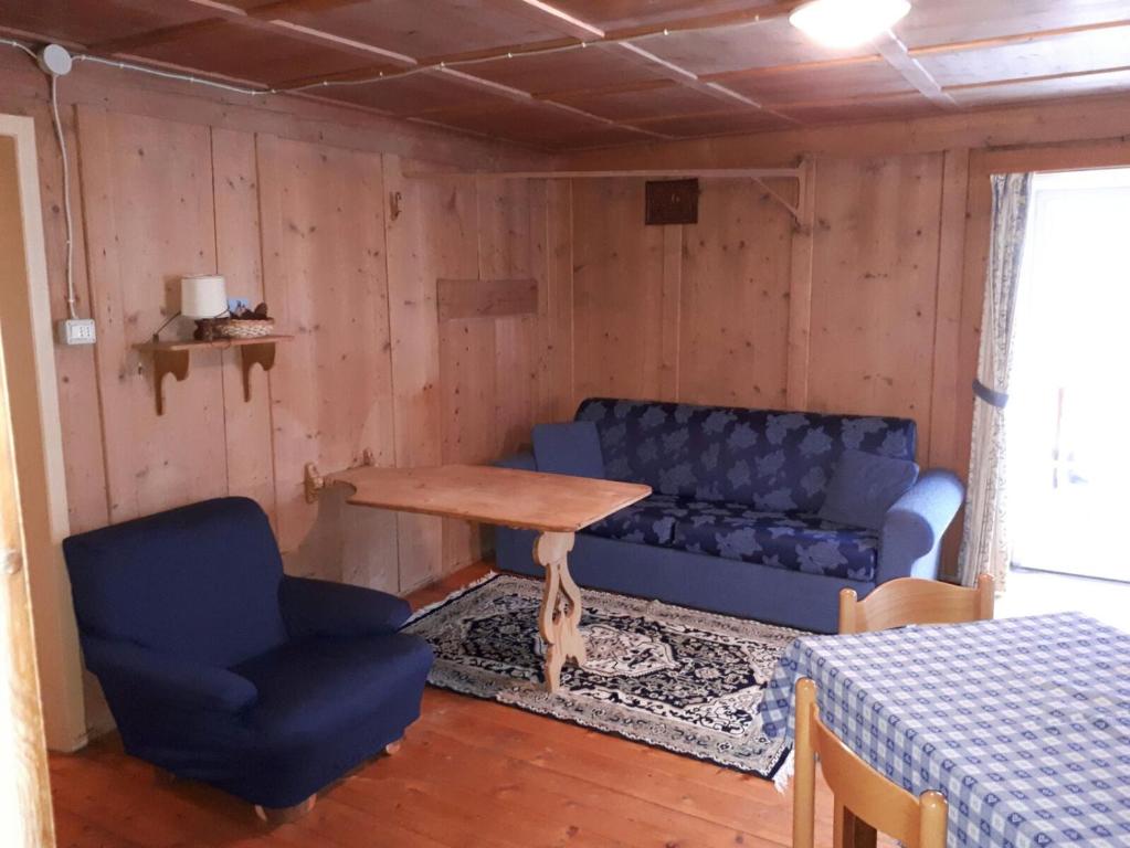 un soggiorno con divano blu e tavolo di Ciasa de Anz a Pozza di Fassa