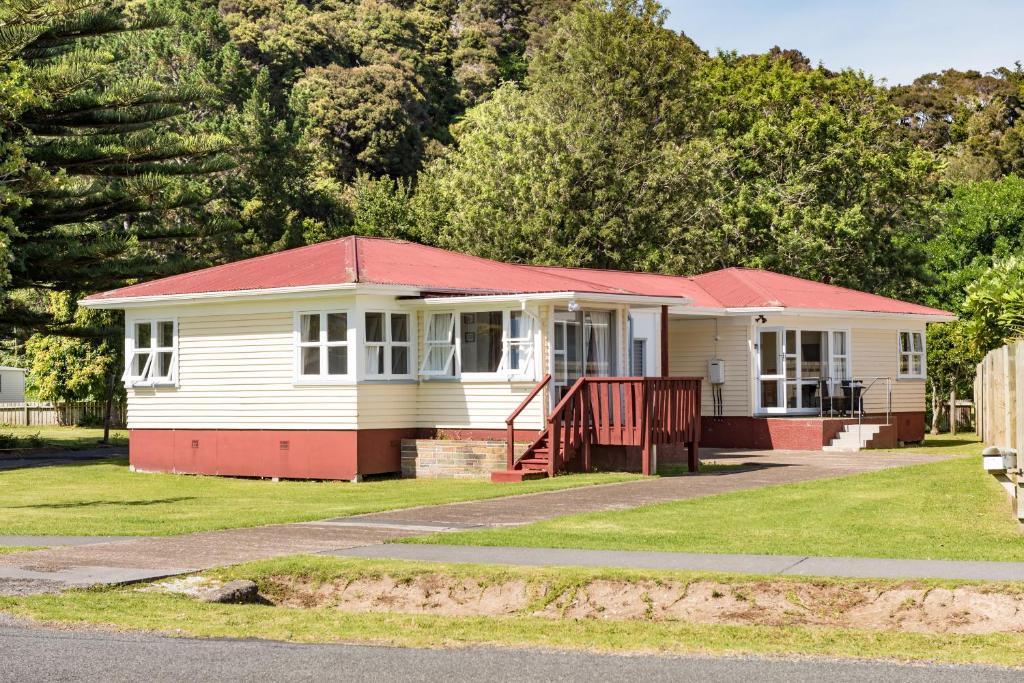 a small house with a red roof on a street at Waitangi Beach Bach 30B in Paihia