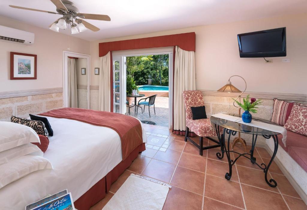 a bedroom with a bed and a tv and a patio at Little Arches Boutique Hotel - Adults Only in Christ Church