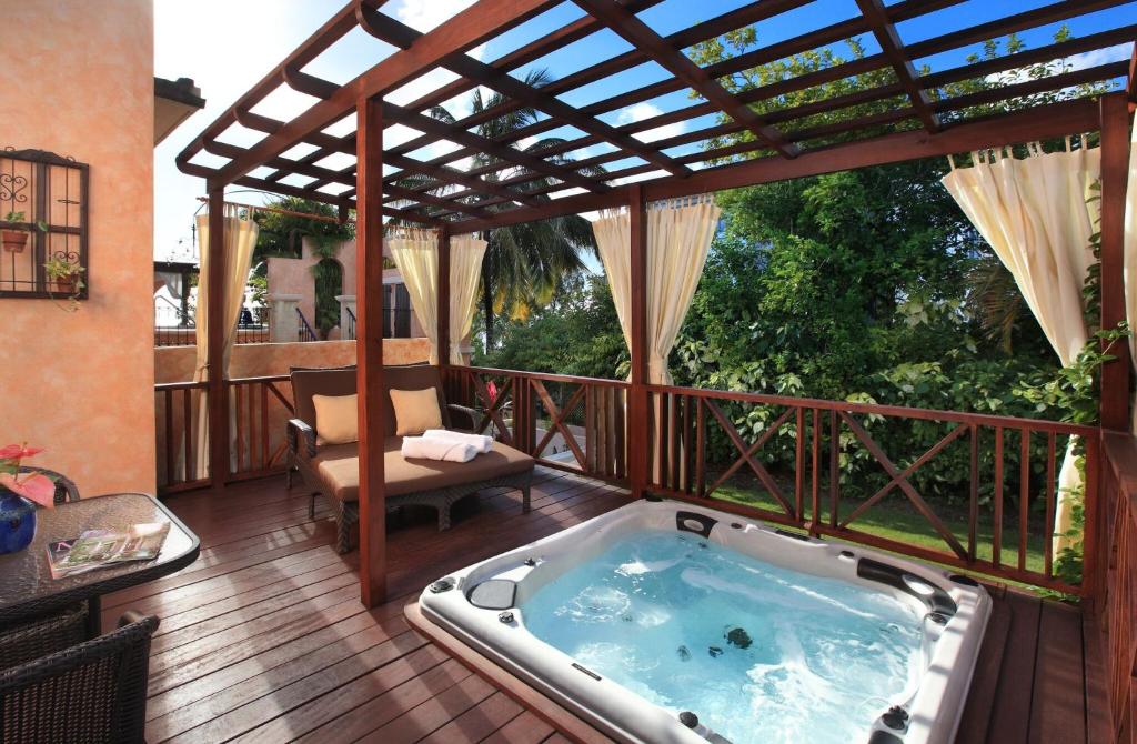 a hot tub on a deck with a pergola at Little Arches Boutique Hotel - Adults Only in Christ Church