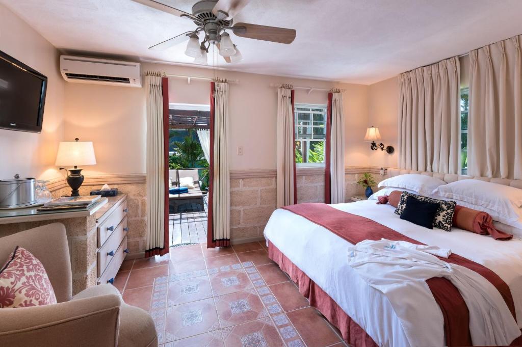 a bedroom with a large bed with a ceiling fan at Little Arches Boutique Hotel - Adults Only in Christ Church