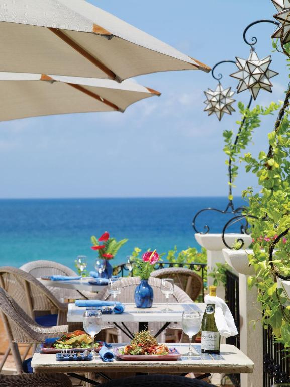 a table with plates of food and a view of the ocean at Little Arches Boutique Hotel - Adults Only in Christ Church