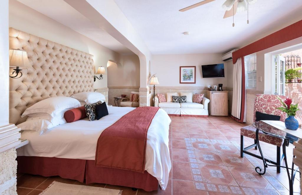 a bedroom with a large bed and a living room at Little Arches Boutique Hotel - Adults Only in Christ Church