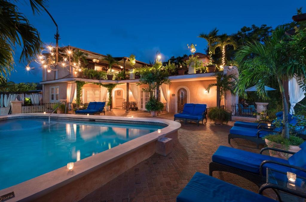 a house with a swimming pool at night at Little Arches Boutique Hotel - Adults Only in Christ Church