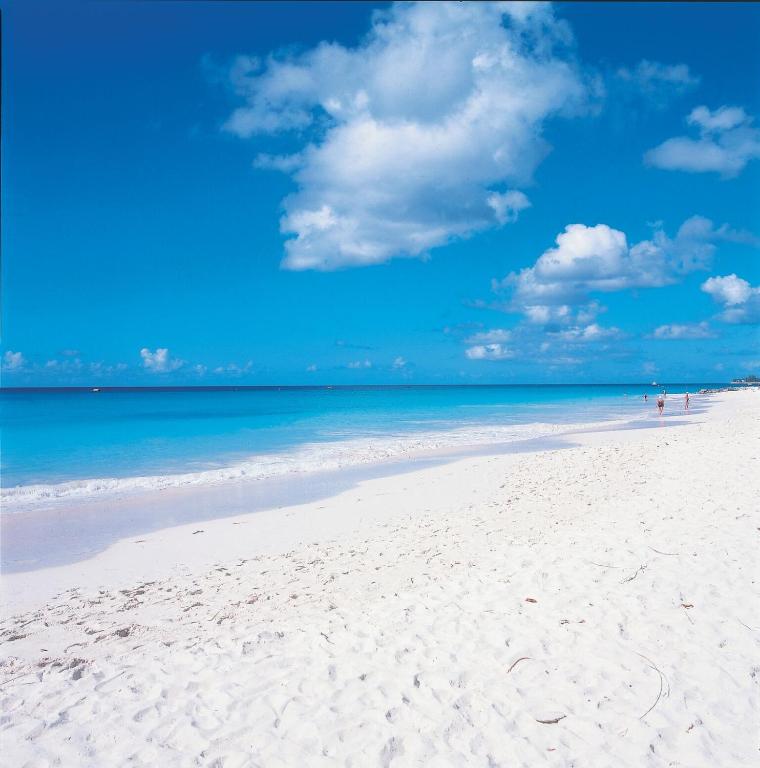 a beach with white sand and a blue sky and clouds at Little Arches Boutique Hotel - Adults Only in Christ Church
