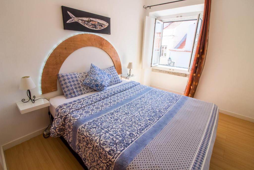 Schlafzimmer mit einem Bett mit einer blauen und weißen Bettdecke in der Unterkunft Apartment São Lourenço in Lissabon