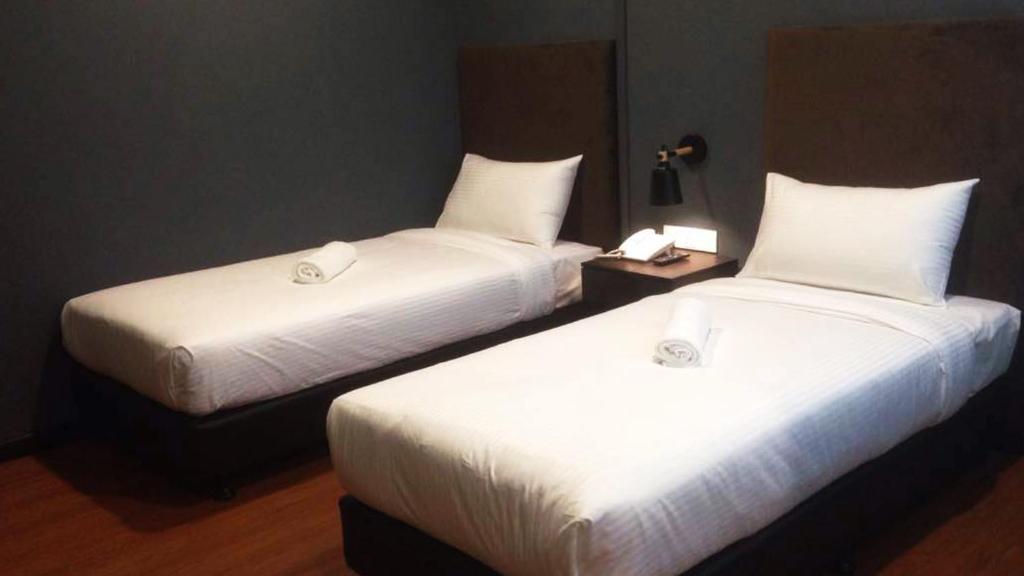 two beds with white sheets in a hotel room at Jenjarom Boutique Hotel in Banting