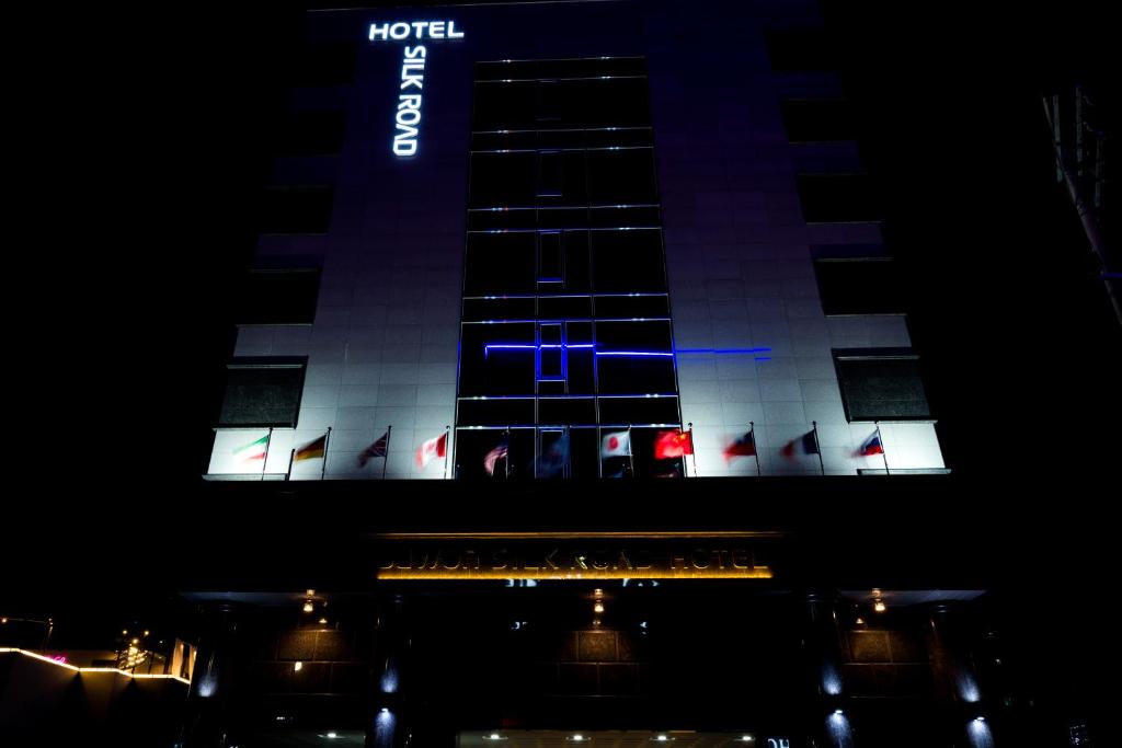 a building with a lit up sign on it at night at Reborn Suwon Silkroad Hotel in Suwon