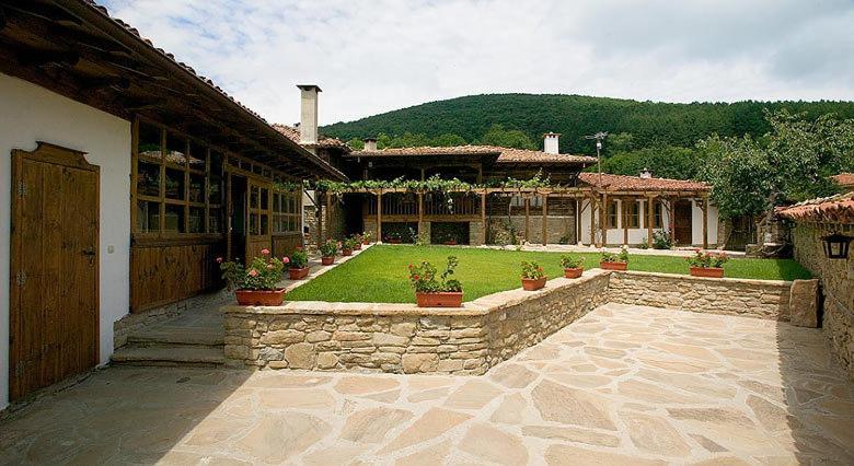 una casa con un patio de piedra con macetas en The House with the Vine Guest House, en Zheravna