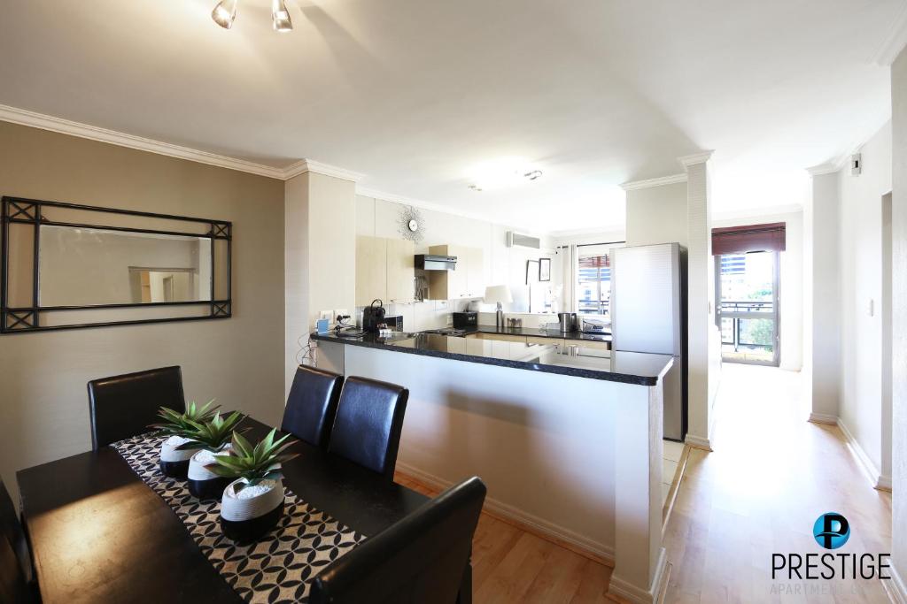 a kitchen and dining room with a table and a bar at Prestige Apartments Sandton at Westpoint in Johannesburg