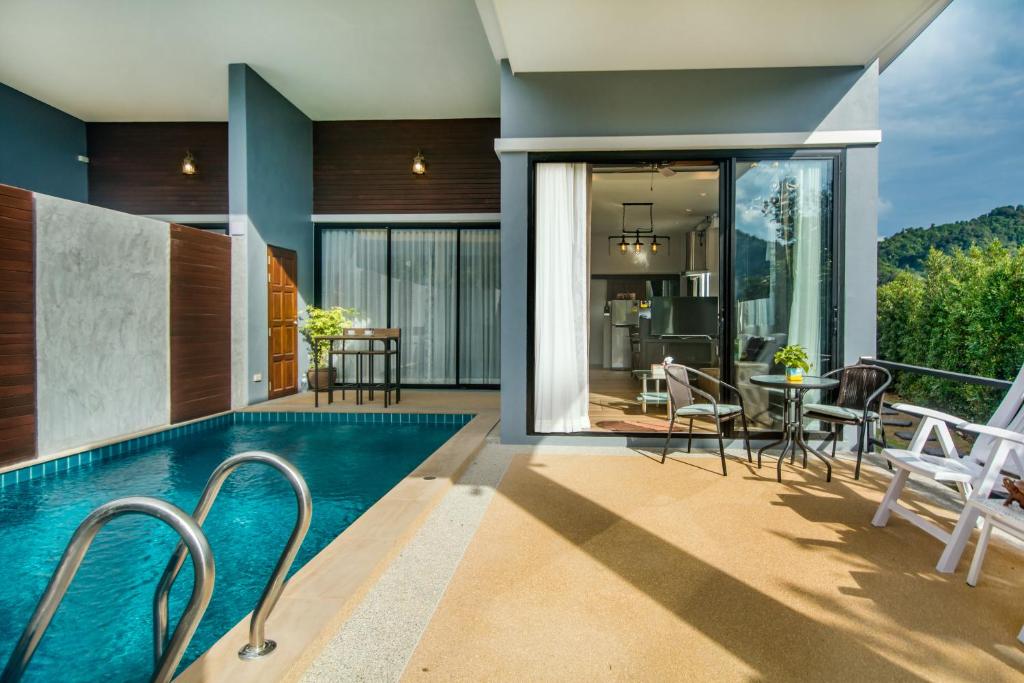 a house with a swimming pool with chairs and a table at KG Private Pool Villa in Ao Nang Beach