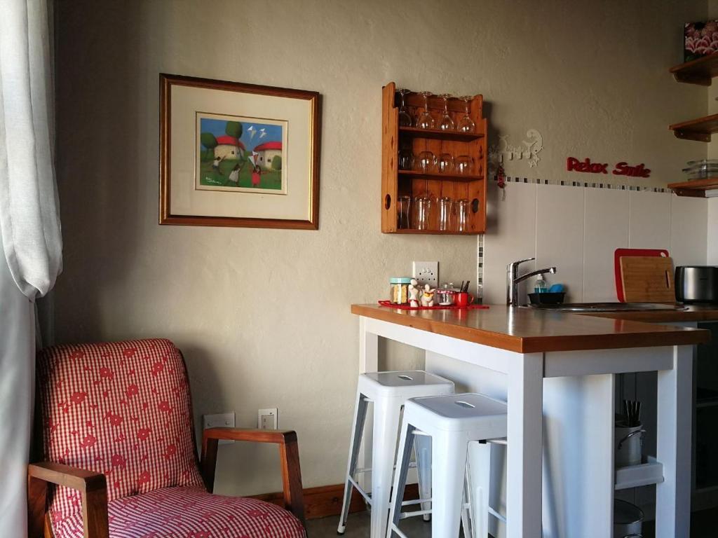 una cocina con barra y un bar con taburetes en Colours of the Sea Apartment, en Struisbaai