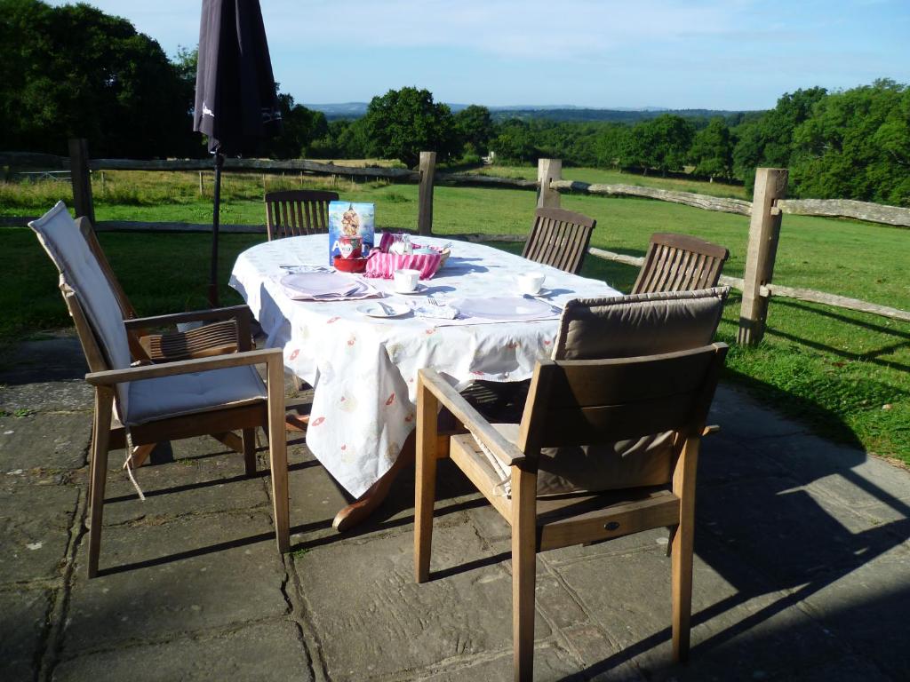 una mesa con 4 sillas y una sombrilla en el patio en Moaps Farm Bed and Breakfast, welcome, check in from 5 pm en Danehill