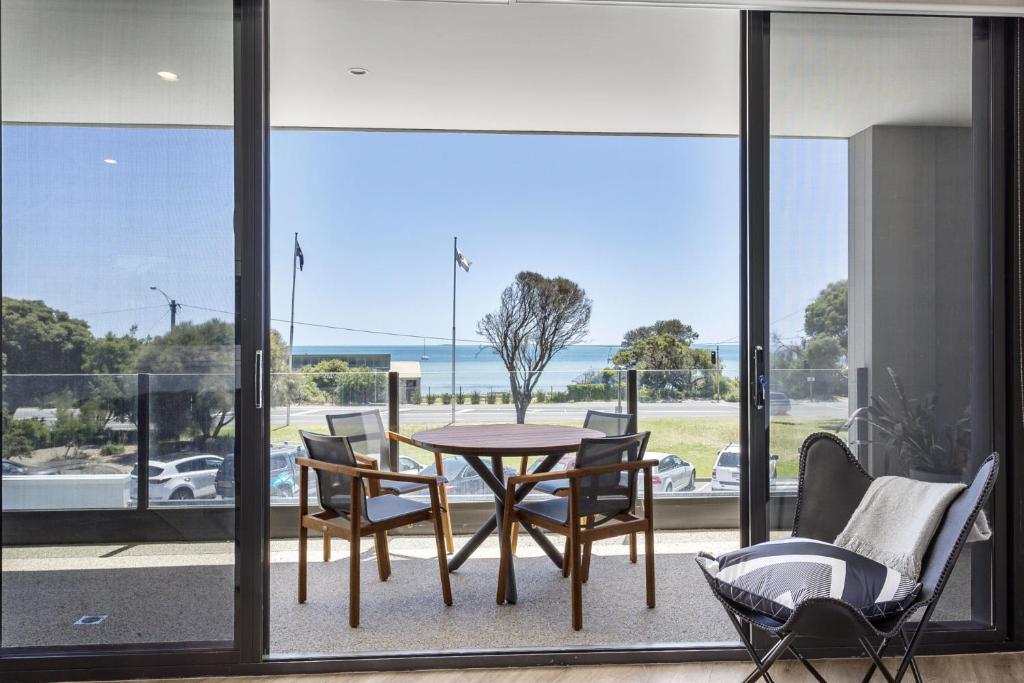 a patio with a table and chairs and a view of the ocean at Blairgowrie Apartment 1 - on the beach in Blairgowrie
