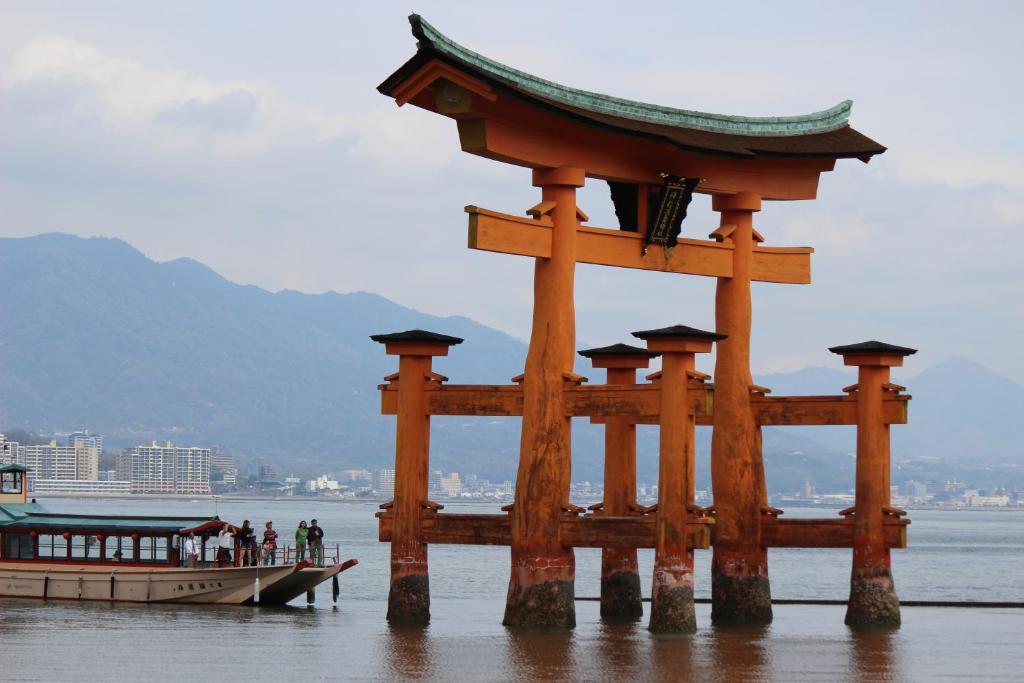 a boat in the water next to a large wooden structure at Guesthouse COCO Hiroshima (Female Only) in Hiroshima