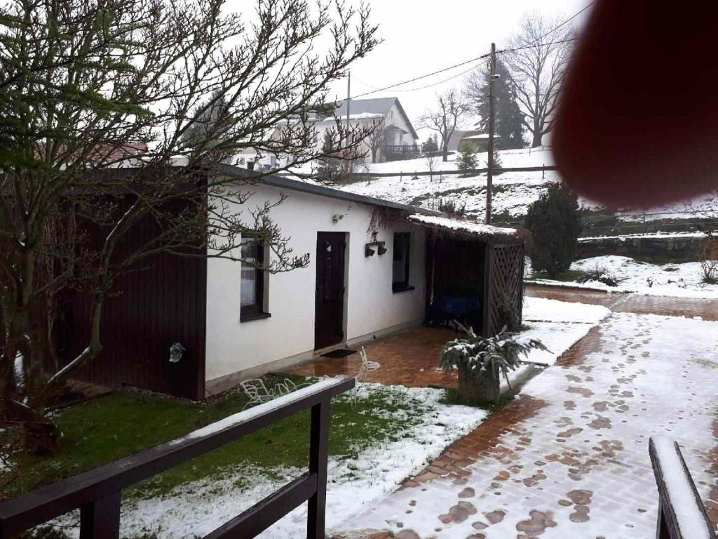 ein Haus mit Schnee auf dem Boden neben einem Zaun in der Unterkunft Ferienwohnung in Reinhardtsdorf