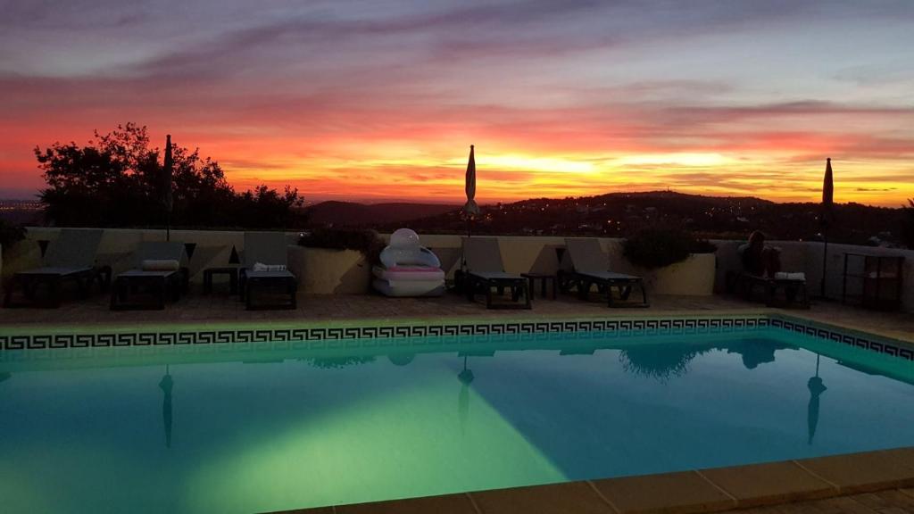 einen Pool mit Sonnenuntergang im Hintergrund in der Unterkunft Felicidade in Loulé