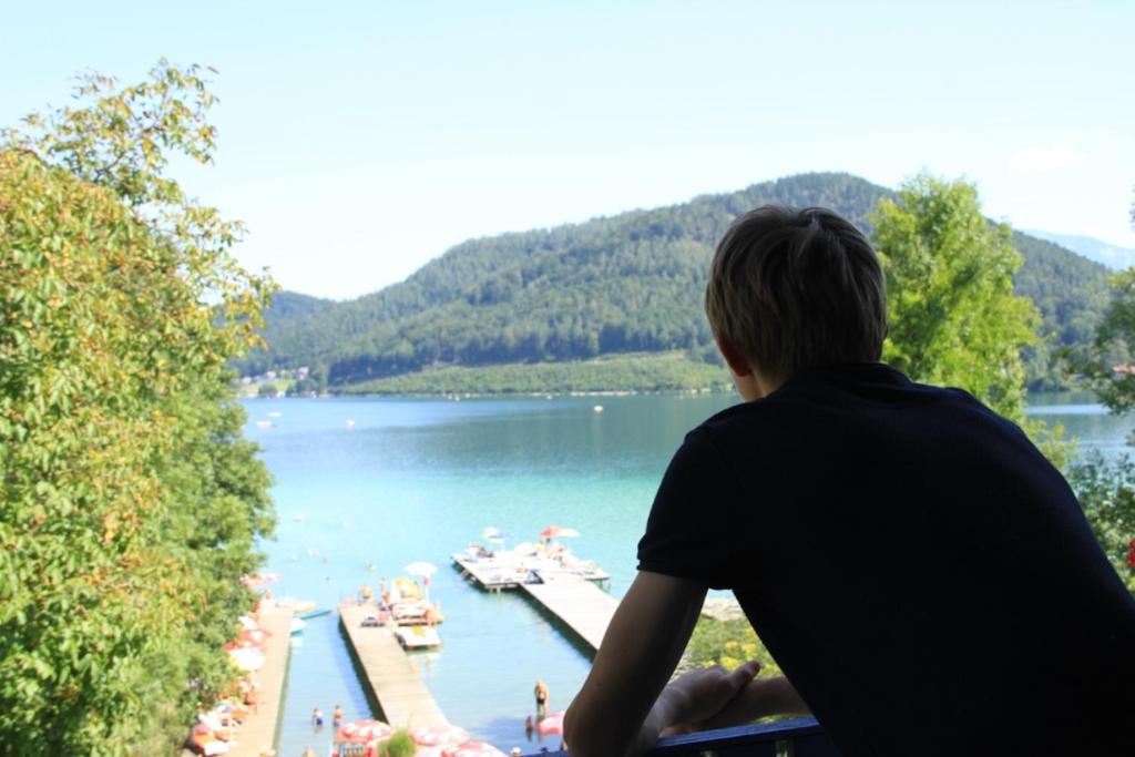 una persona mirando al lago desde un balcón en das West en Sankt Kanzian