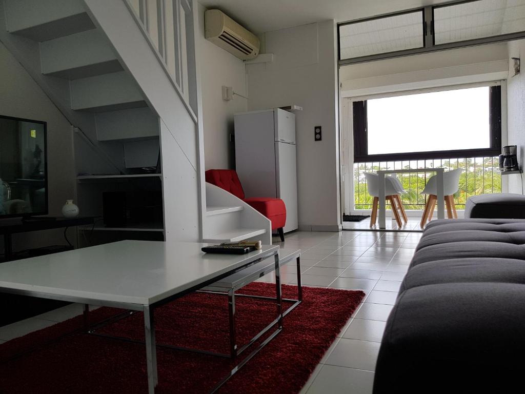a living room with a white table and a red rug at Joli T2 à 5 min de la plage in Le Gosier