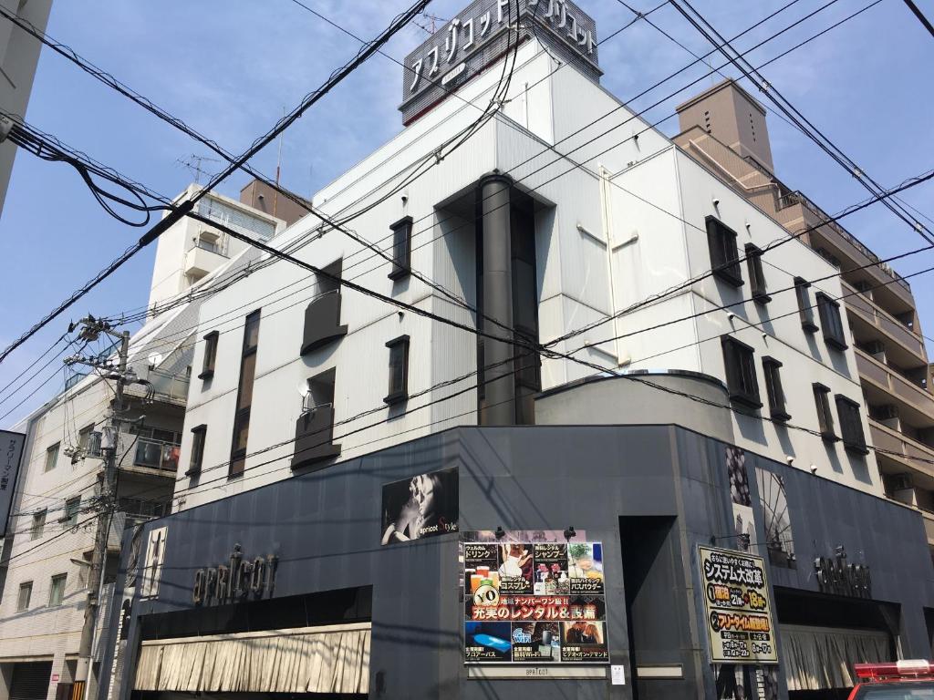 a white building with wires above it on a street at Hotel Apricot (Adult Only) in Hiroshima