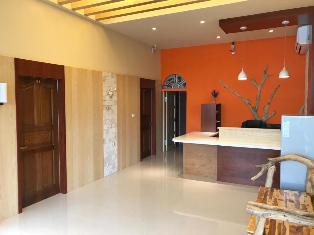 an empty lobby with orange walls and a counter at Home Coming in Xiaoliuqiu