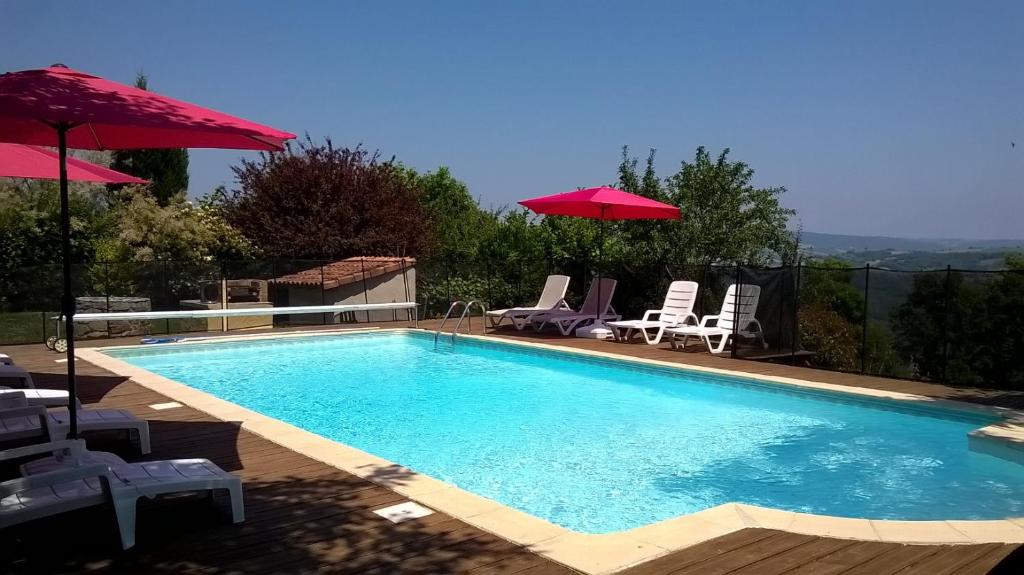 ein Pool mit Stühlen und Sonnenschirmen daneben in der Unterkunft La Caze Gites in Broquiès