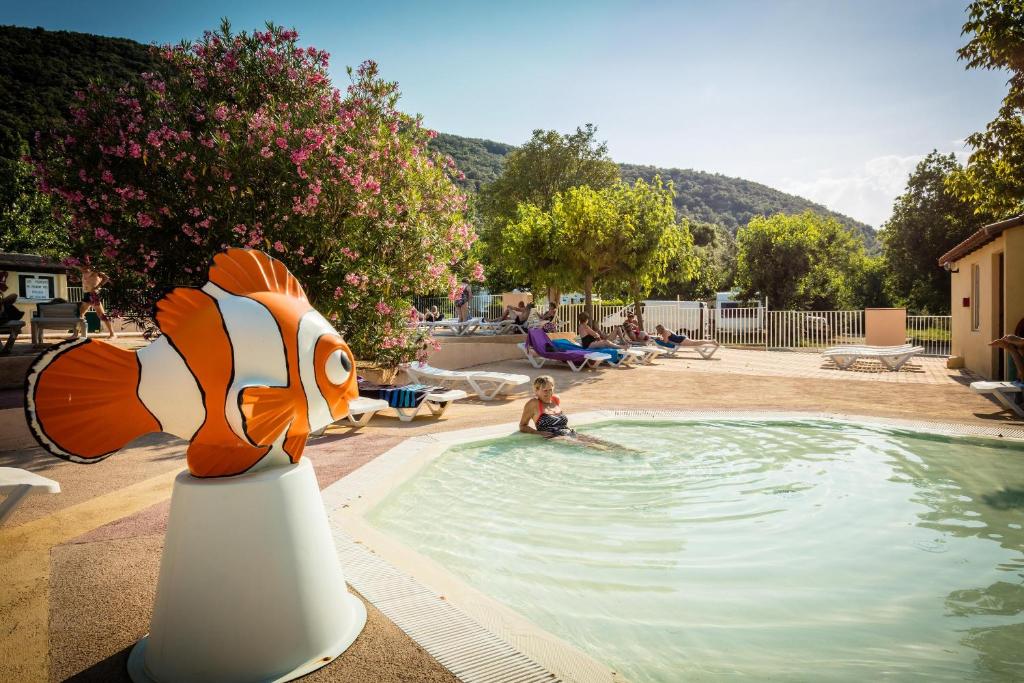 een meisje zit in een zwembad met een visbeeld bij Aloha Camping Club in Reynès