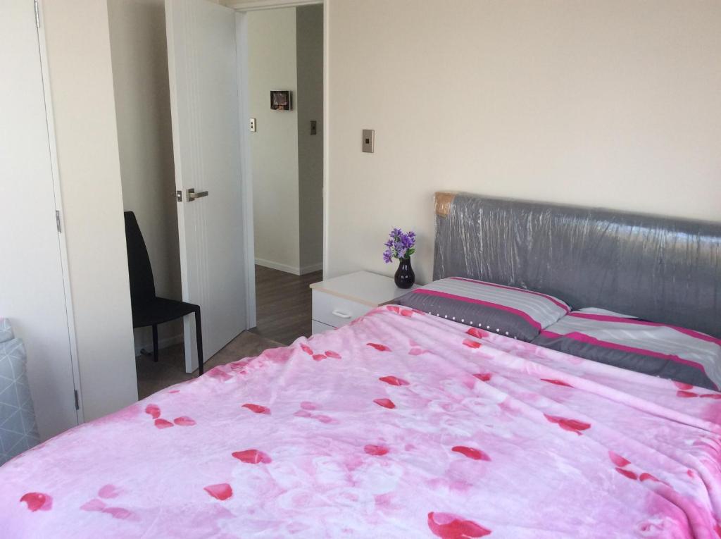 a bedroom with a pink bed with roses on it at Brand new bedroom in Karaka (Auckland) in Auckland