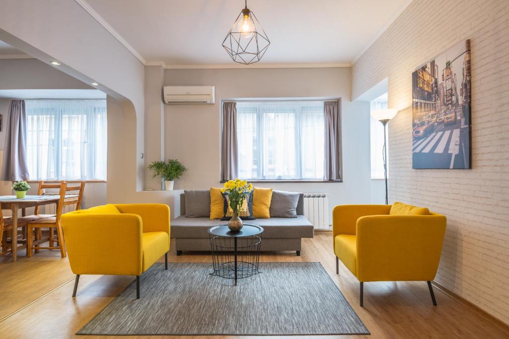 a living room with two yellow chairs and a couch at 5th Avenue Sofia | Two Bedroom, Two Bathroom, Positano Street Suite in Sofia