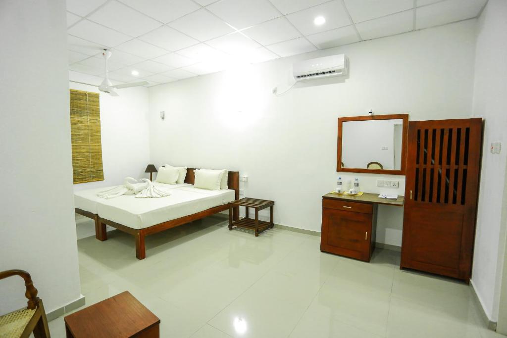 biały pokój z łóżkiem i lustrem w obiekcie Candila Hotel & Sports Club w mieście Habarana