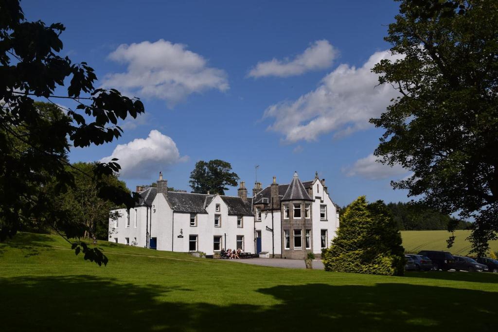 a large white house on a green lawn at Saplinbrae Hotel and Lodges in Mintlaw