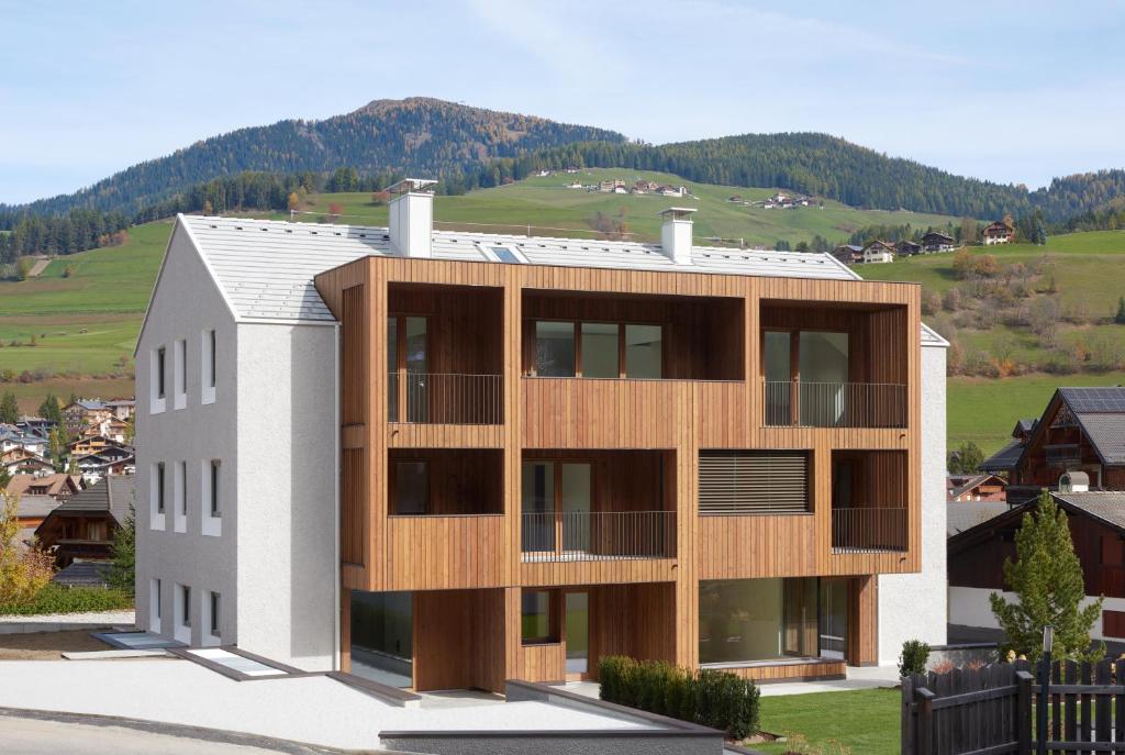 budynek z drewnianą fasadą z górami w tle w obiekcie Living Nature Appartements w mieście San Vigilio di Marebbe