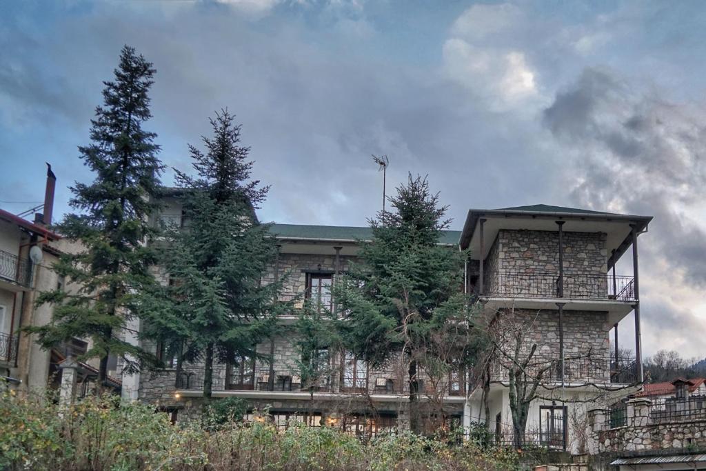 un gran edificio de ladrillo con árboles delante de él en Guesthouse Alexandra, en Eptalofos