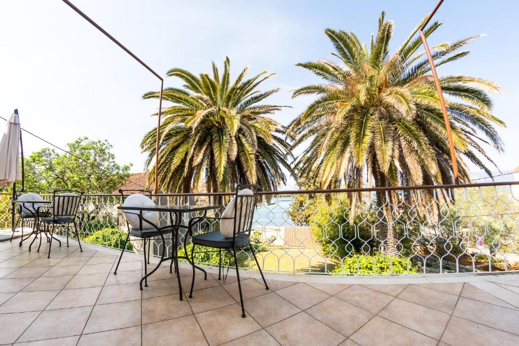 a patio with tables and chairs and palm trees at Stipica Apartment in Lumbarda