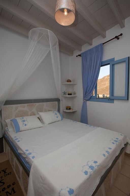 a bedroom with a bed with a mosquito net at Lampi's House in Patmos