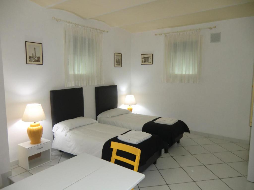 ボローニャにあるVilla Almaのベッドルーム1室(ベッド2台、テーブル、ランプ付)