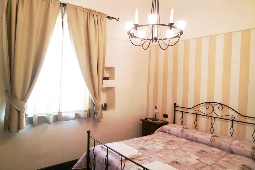 um quarto com uma cama com um lustre e uma janela em Al Vecchio Cellaio Historical Guest House em SantʼAntonio Abate