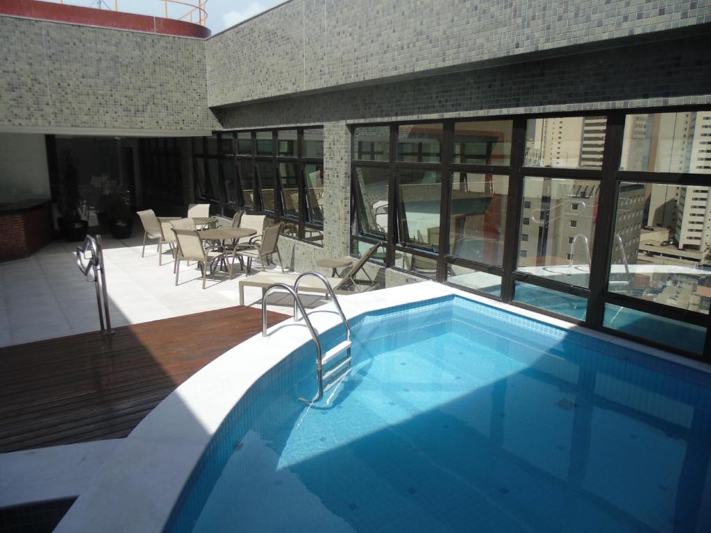 a swimming pool with chairs and tables in it at Marante Executive Hotel in Recife