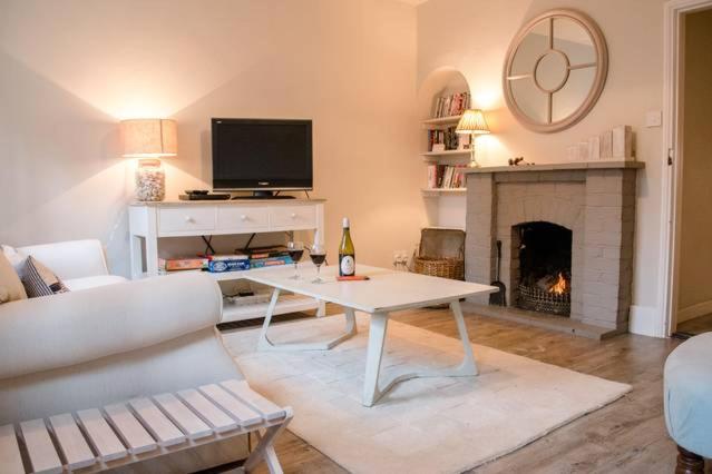 a living room with a table and a fireplace at Castle Cottage Orford in Orford